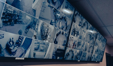 Three-monitor video wall in the back office — private, independent camera monitoring for management. 